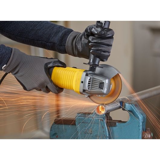 STANLEY FMEG210K angle grinder in use, cutting metal pipe with sparks, close-up photography.