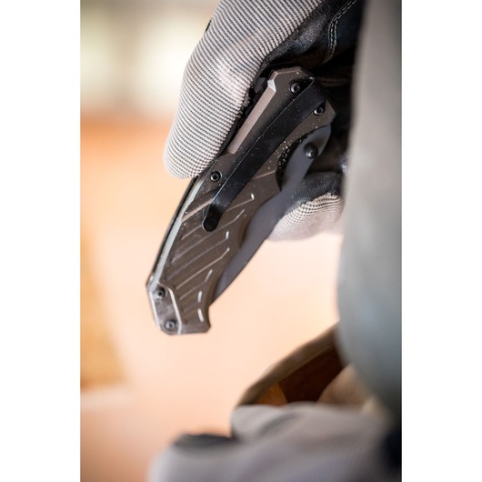 Close-up photo of a gloved hand holding a STANLEY FMHT0-10311 folding utility knife with black handle.