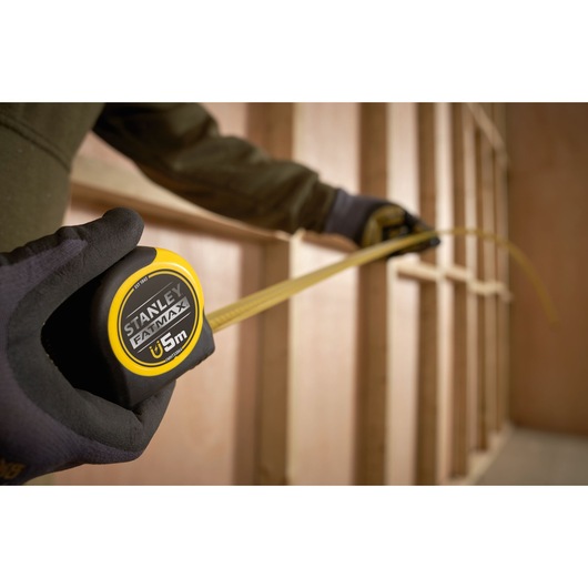 Photo of STANLEY FATMAX tape measure FMHT0-33864 being used to measure a wooden frame.
