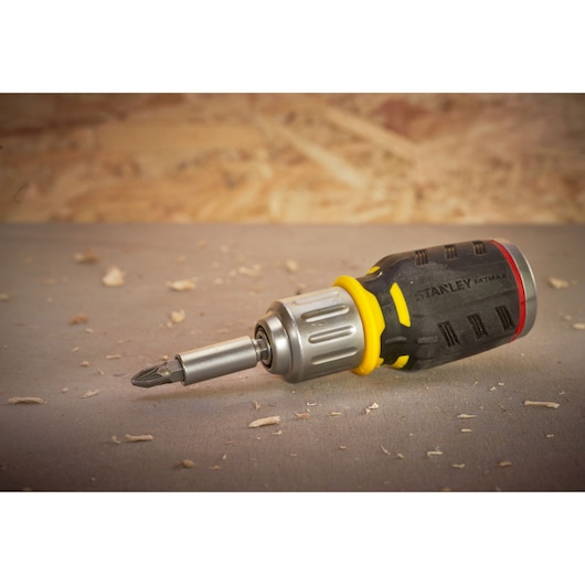 STANLEY FMHT0-62688 ratcheting screwdriver with black and yellow handle, side angle, on workbench.