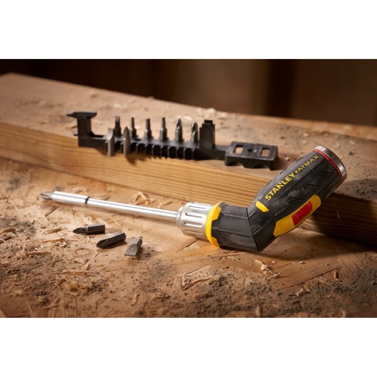 STANLEY FMHT0-62691 ratcheting screwdriver with black and yellow handle, bit holder and bits on wood.