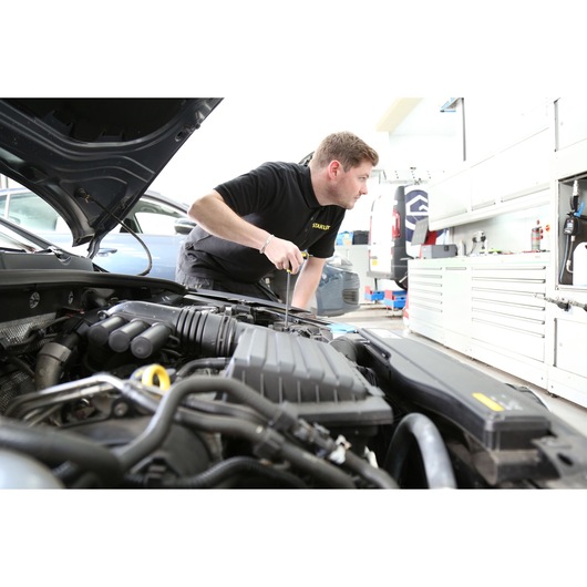 Photo of STANLEY FMHT0-69049 screwdriver used by technician working on car engine in workshop.