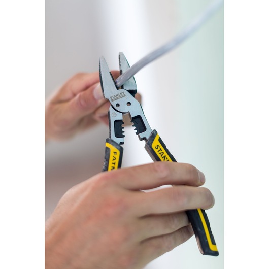 STANLEY FMHT0-75469 pliers with black and yellow handles used to strip a wire, close-up photo.