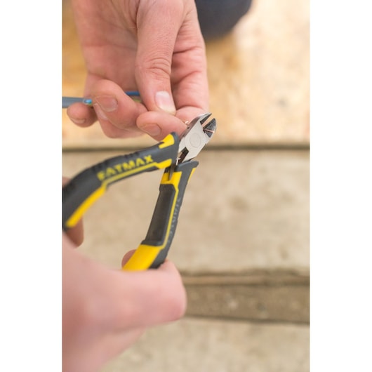 Photo of STANLEY FMHT0-80541 diagonal cutting pliers with yellow and black grips cutting wire, close-up.