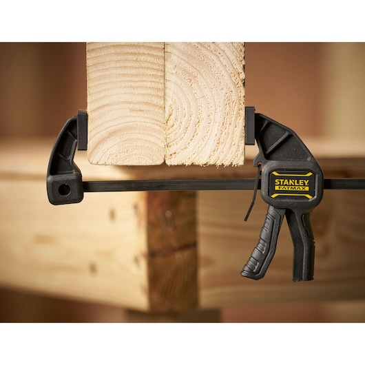 STANLEY FMHT0-83231 clamp holding two wooden boards, close-up in workshop setting.