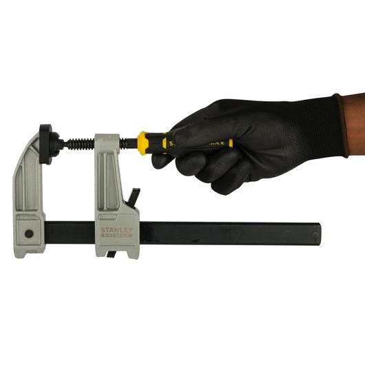 Photo of STANLEY FMHT0-83244 bar clamp with black-gloved hand tightening handle, front angle.