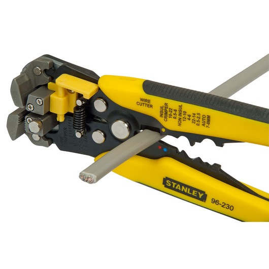 STANLEY FMHT0-96230 wire stripper and cutter tool in use with yellow and black handles, close-up on white background.