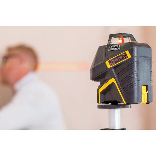 STANLEY FMHT1-77416 black and yellow laser level mounted on tripod, with blurred background.