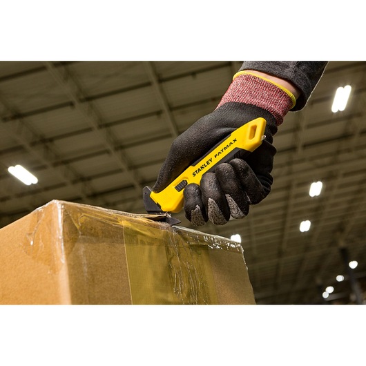 STANLEY FMHT10358-0 utility knife cutting tape on a cardboard box, worker wearing black gloves.
