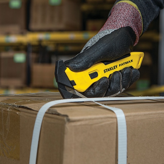 STANLEY FMHT10358 utility knife cutting box strap in warehouse, close-up photography.