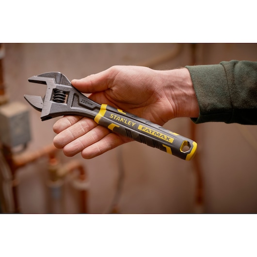 Photo of STANLEY FMHT13127-0 adjustable wrench with yellow and black handle held in hand, indoor setting.