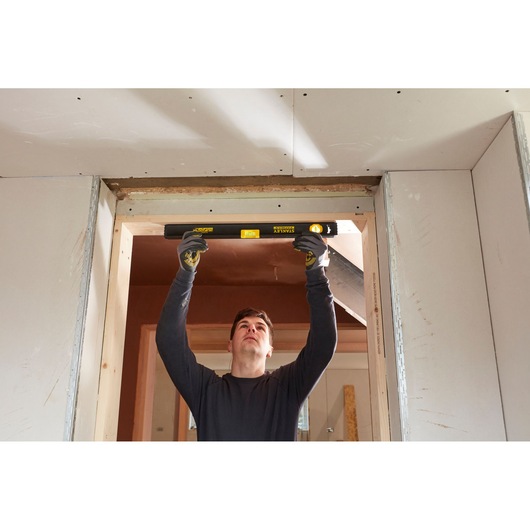 Person using STANLEY FMHT42554-1 spirit level to check doorway alignment during construction.