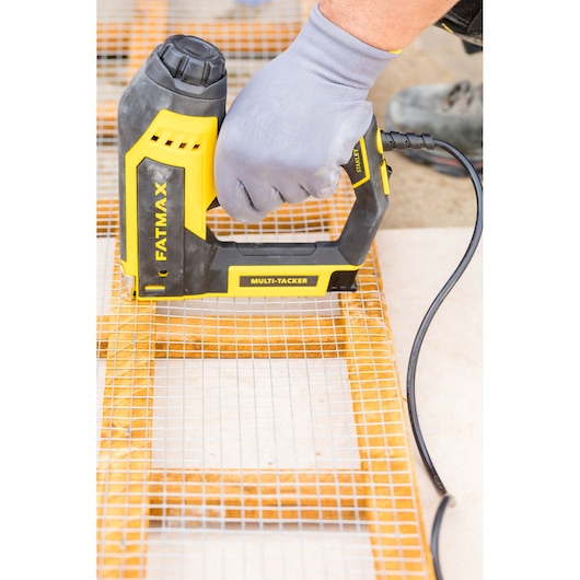 Photo of STANLEY FATMAX FMHT6-75934 electric multi-tacker stapling wire mesh to wood, close-up in use.