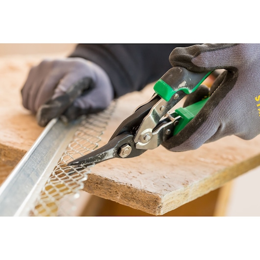 STANLEY FMHT73557-0 aviation snips cutting metal mesh, close-up angle, worker wearing gloves.