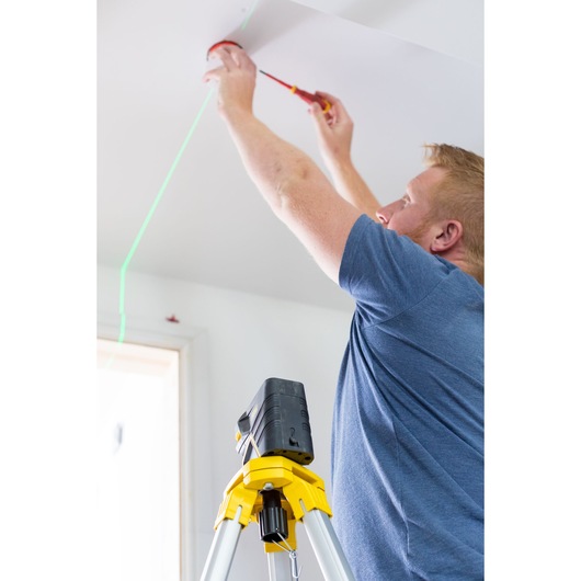 STANLEY FMHT77598-1 laser level on tripod projects green line indoors during ceiling installation.