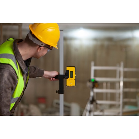 Photo of a worker using a STANLEY FMHT77653-0 laser detector attached to a rod at a construction site.