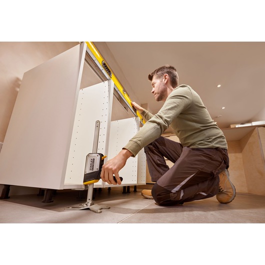Photo of person using STANLEY FMHT83550-1 cabinet jack tool to level kitchen cabinets during installation.