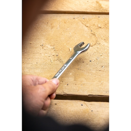 STANLEY FMMT13036-0 open-end wrench held by hand on a wooden surface.