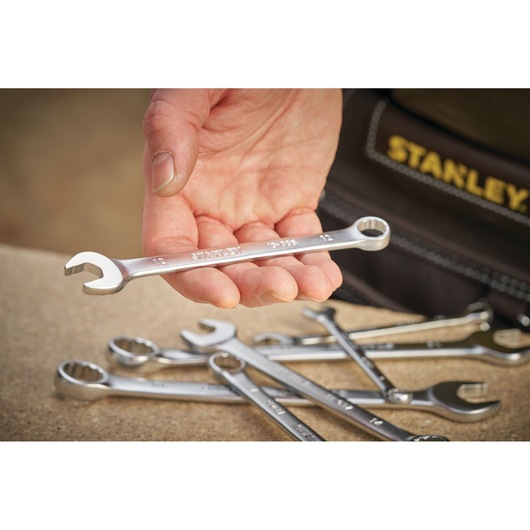 STANLEY FMMT13038-0 combination wrench held in hand, with additional wrenches on a workbench.