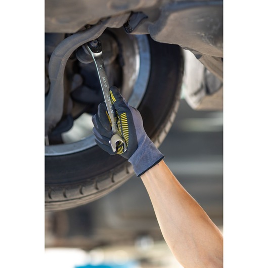 STANLEY FMMT13089-0 wrench used by gloved hand to repair car wheel, close-up photo.