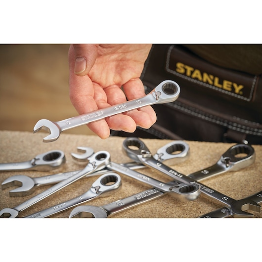 Photo of STANLEY FMMT13095-0 ratcheting combination wrench held by hand, with other wrenches on a workbench.
