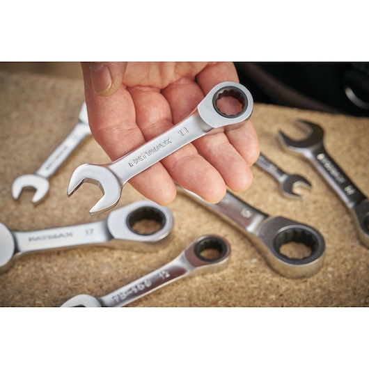Photo of STANLEY FMMT13113-0 ratcheting combination wrenches, one held in hand, others on work surface.