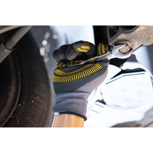 STANLEY FMMT13115-0 wrench held by gloved hand tightening bolt near tire, close-up photography.