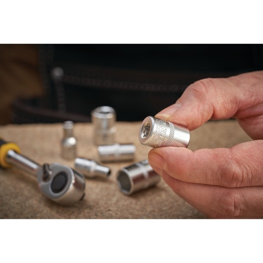 Photo of STANLEY FMMT17186-0 socket held in hand with ratchet and sockets on workbench.