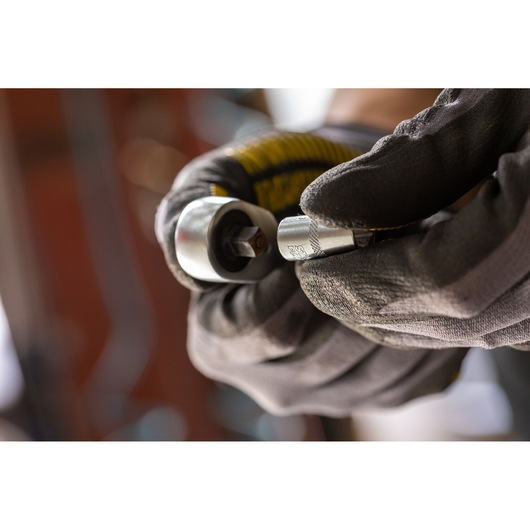 Photo of STANLEY FMMT17191-0 socket adapter held by gloved hand, close-up view, tool detail.