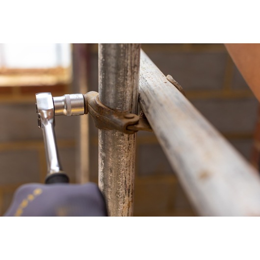 STANLEY FMMT17235-0 ratchet tool in use tightening metal scaffold clamp, close-up photography.