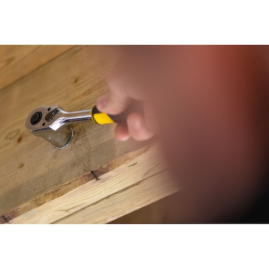 STANLEY FMMT82676-0 ratchet wrench with yellow handle in use on wooden surface.