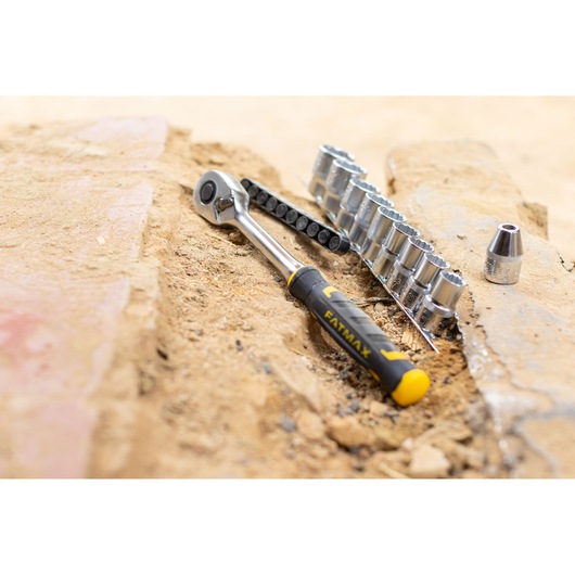 STANLEY FMMT82680-0 ratchet and socket set with yellow and black handle on sandy ground, front angle.