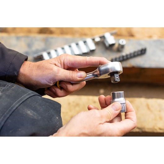 STANLEY FMMT82680-0 socket wrench set in use, close-up of hands holding ratchet and socket.
