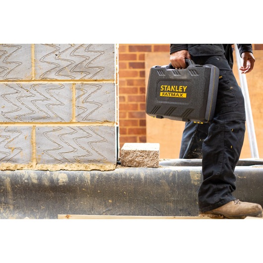 Stanley FMMT82684-1 FATMAX hard tool case carried by worker at construction site.