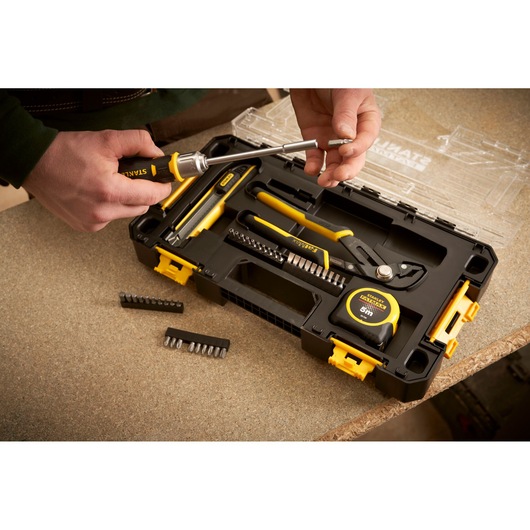 STANLEY FMMT98106-1 hand tool set in open black and yellow case, screwdriver, pliers, tape measure, assorted bits.