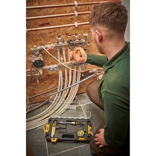 Stanley FMMT98106-1 toolkit in use by technician for plumbing, open case showing tools on floor.