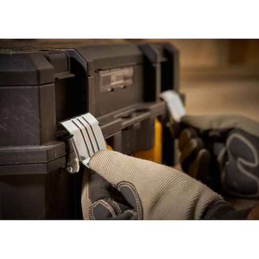 Photo of STANLEY FMST1-71967 toolbox latch being operated with gloved hands, close-up angle.