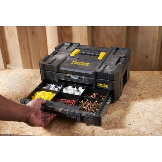 STANLEY FMST1-71969 organizer box with open front drawer filled with assorted hardware, shown on workbench, angled view.