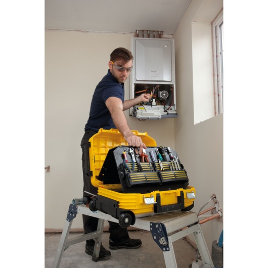 Photo of STANLEY FMST1-72383 tool case open on a step ladder, with technician working on a wall-mounted unit.