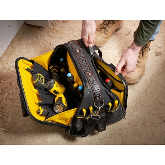 STANLEY FMST1-73607 tool bag with yellow interior, filled with tools, shown from above on jobsite floor.