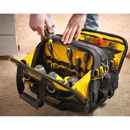 STANLEY FMST1-73607 tool bag with multiple hand tools, yellow and black, angled view on worksite.