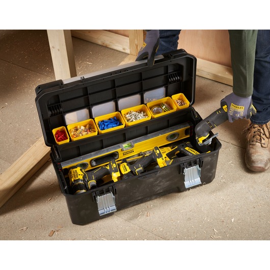 STANLEY FMST1-75791 toolbox with yellow compartments and power tools, top view on workshop floor.