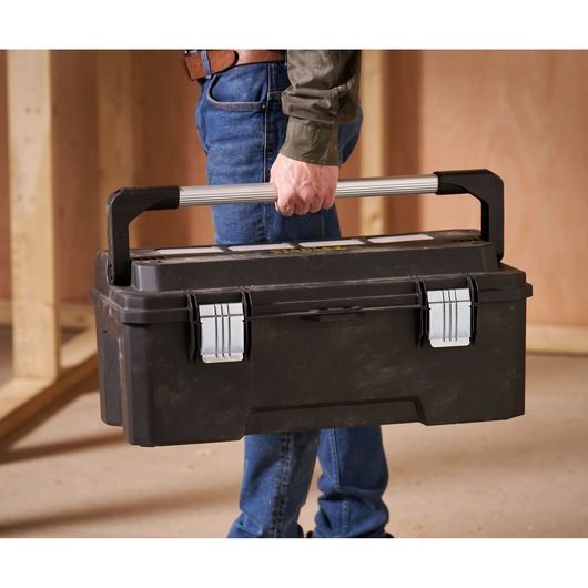 STANLEY FMST1-75791 toolbox with silver metal handle and latches carried indoors by person wearing jeans.