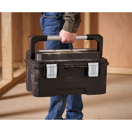 STANLEY FMST1-75792 toolbox with metal latches, carried by hand in a workshop setting.