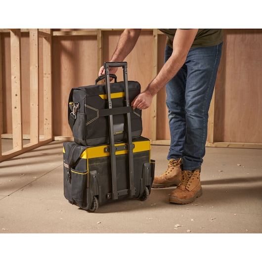 STANLEY FMST1-80149 rolling tool bag and backpack in construction setting, side angle.