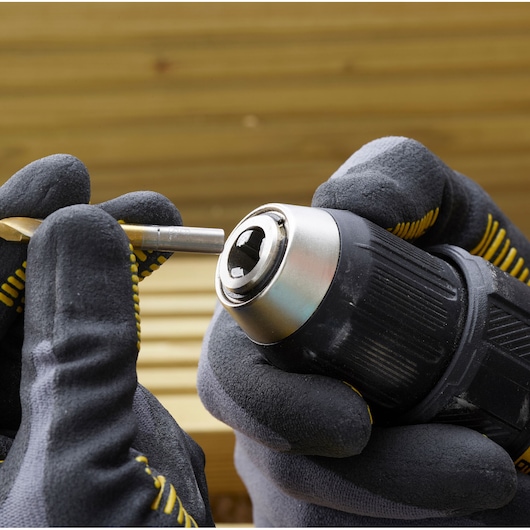 STANLEY SFMCD710C2K drill with gloved hands inserting bit, product shown close-up