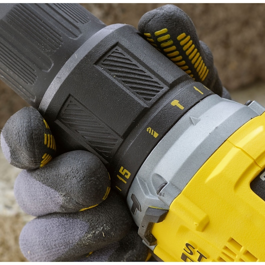 Close-up photo of STANLEY SFMCD715D2F cordless drill with gloved hand adjusting torque settings.
