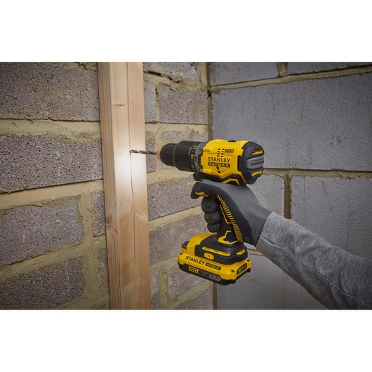 Photo of STANLEY SFMCD715D2K cordless drill in use, yellow and black, drilling into wood.