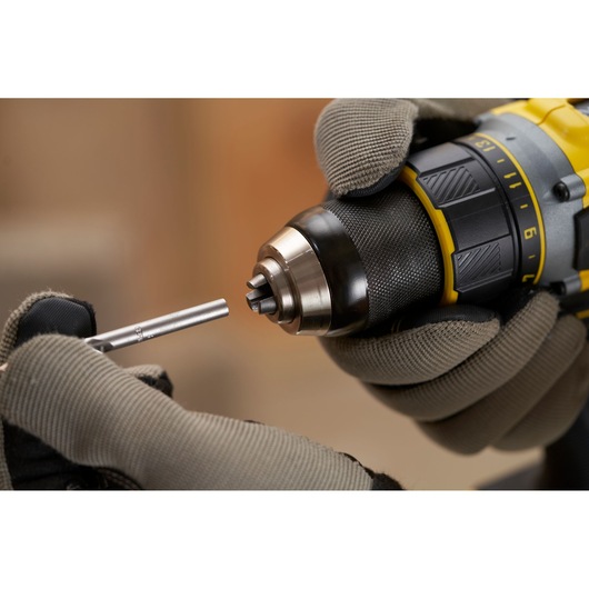 STANLEY SFMCD720B cordless drill with gloved hands inserting drill bit, close-up side angle.