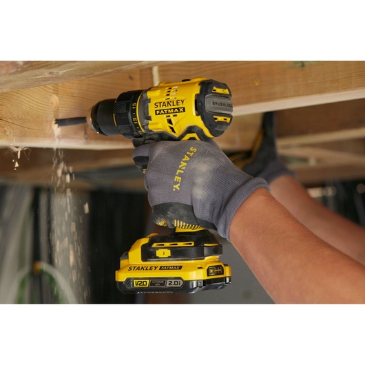 STANLEY SFMCD720B cordless brushless drill used for wood drilling, yellow and black, close-up action.